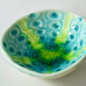 A large handmade porcelain trinket dish, glazed in shades of green, blue and yellow