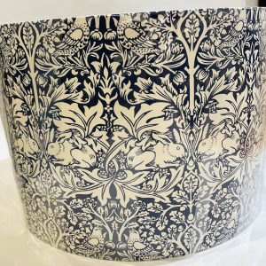 Lampshade, rabbit and bird in foliage against dark blue background