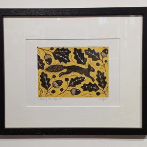 Framed lino cut print of a leaping red squirrel and acorn design (mustard background)